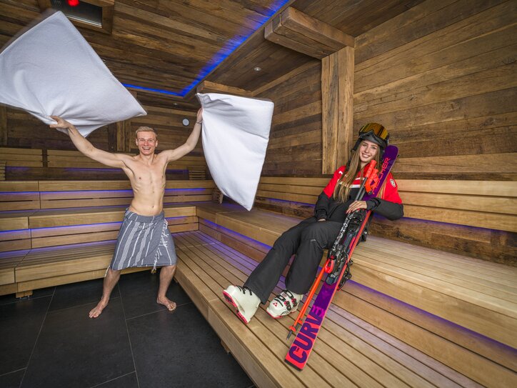 Aufgussmeister mit Skifahrerin in Sauna