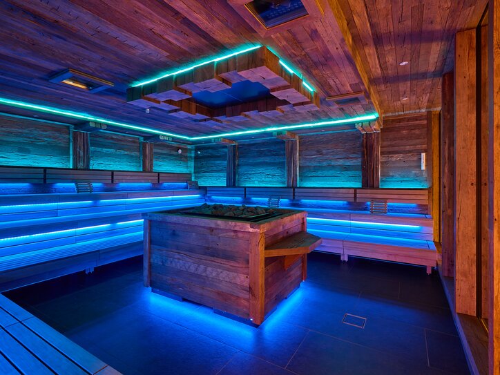 Wooden sauna with blue light and heating element in the middle