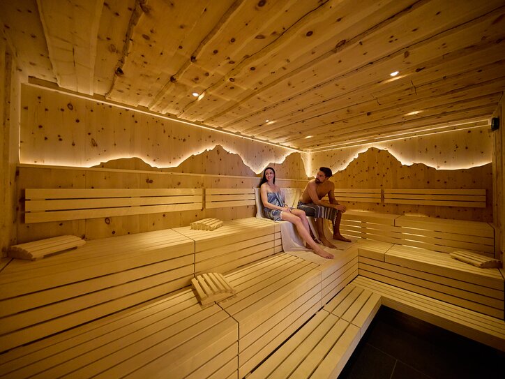 Two People in a Sauna with, wooden benches, and light