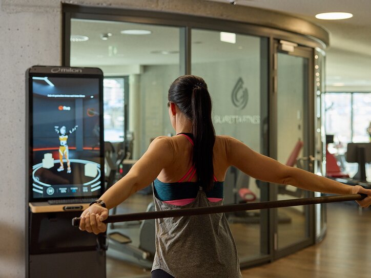 A woman exercising with a fitness machine in front of a digital screen