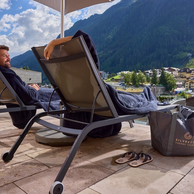 Two guests relax on loungers with mountain view