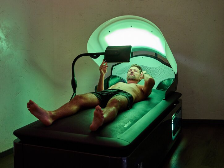 Ein Mann erhält eine Wassermassage auf einer Wellys-Systemliege und schaut dabei auf einen Bildschirm