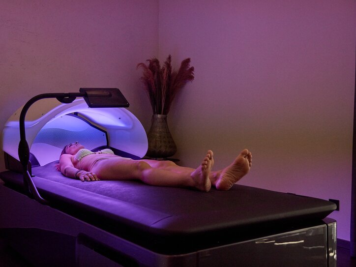 Frau auf der Wassermassage-Liege von Wellsystem, umgeben von sanftem Licht in entspannter Atmosphäre