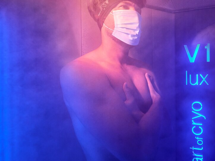 Kältekammer mit blauer Beleuchtung, dichter Nebel und Person während der Kryotherapiebehandlung