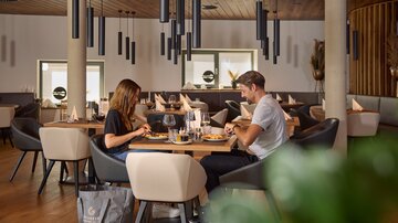 Zwei Personen beim Essen in der Grill Lounge mit stilvollem Holzdekor und warmem Licht