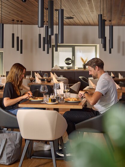 Two people dining in the Grill Lounge with stylish wooden decor and warm lighting.