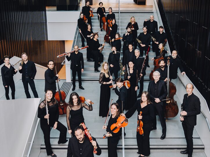 Orchester in schwarzer Kleidung mit Instrumenten auf Treppe